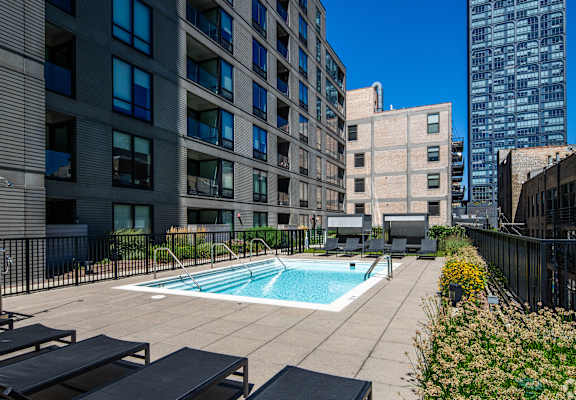 A swimming pool surrounded by lounge chairs and buildings.