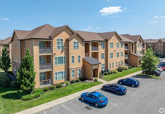 an apartment building with cars parked in a parking lot