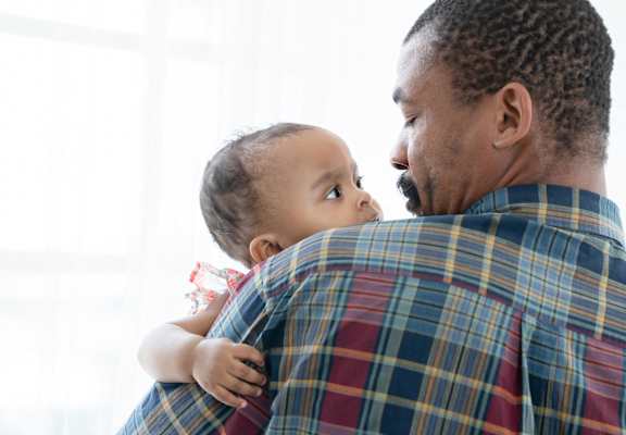 A man in a plaid shirt is holding a baby.