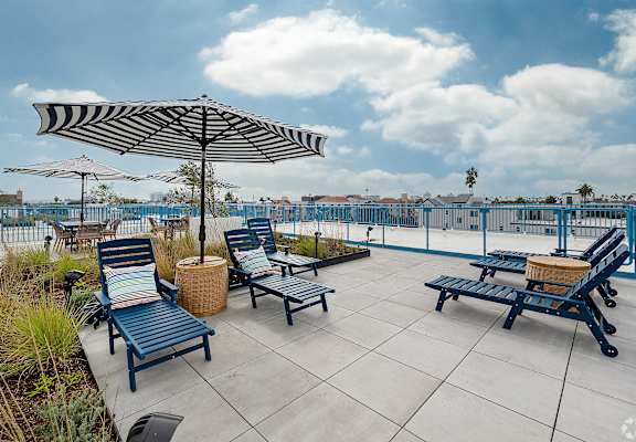 A patio with blue chairs and a striped umbrella.