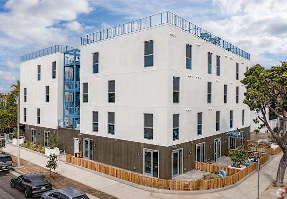 A white building with a blue balcony on the top floor.