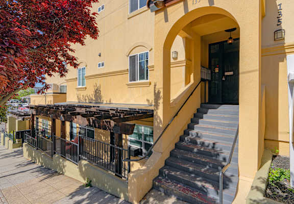 A building with a staircase leading to a black door.