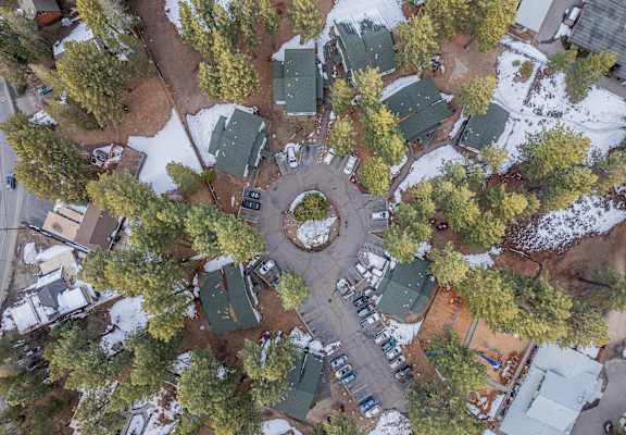 A bird's eye view of a snowy parking lot surrounded by trees.