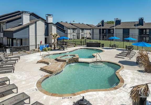 a resort style pool with chairs and umbrellas in front of a building