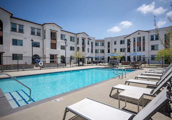 A swimming pool surrounded by sun loungers in front of apartment buildingsat Vintage at Anacapa Canyon, Camarillo