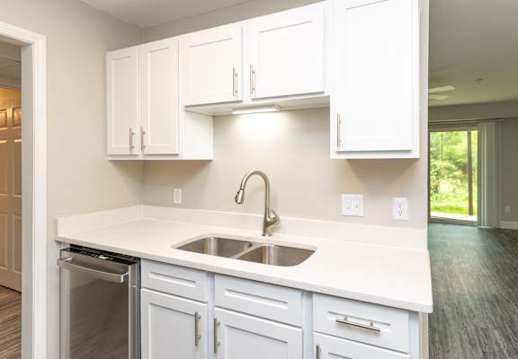 an empty kitchen with white cabinets and a sink