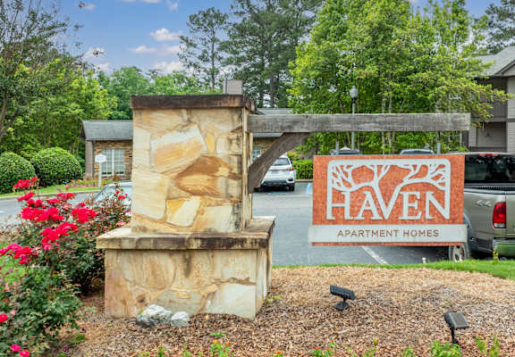 a sign for heaven apartment homes in front of a parking lot