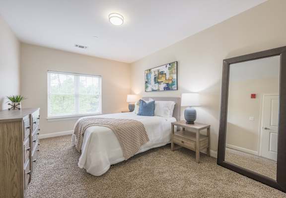 A bedroom with a bed, a nightstand, and a mirror.