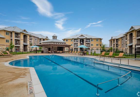 A large swimming pool in front of apartment buildings.