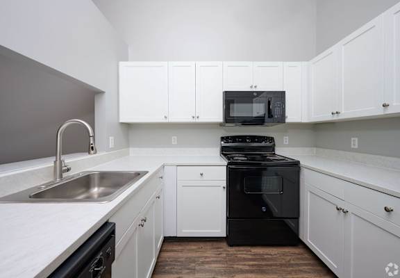 a kitchen with white cabinets and black appliances and a sink at Centerpointe Apartments, Canandaigua