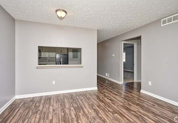 an empty living room with a window and a kitchen at Centerpointe Apartments, Canandaigua