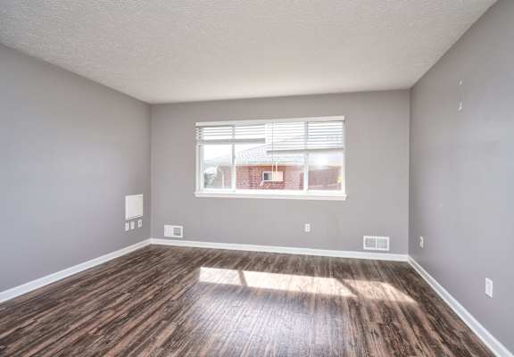 an empty living room with wood floors and a window at Centerpointe Apartments, Canandaigua