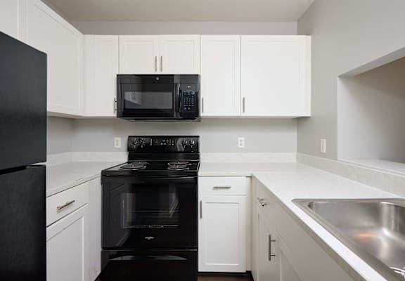 a kitchen with black appliances and white cabinets at Centerpointe Apartments, Canandaigua