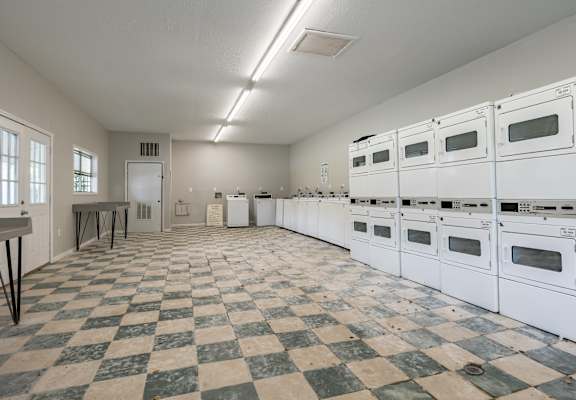 A large empty room with checkered floor and white appliances.