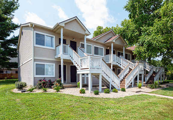 A two-story house with a deck and stairs leading to the second floor.