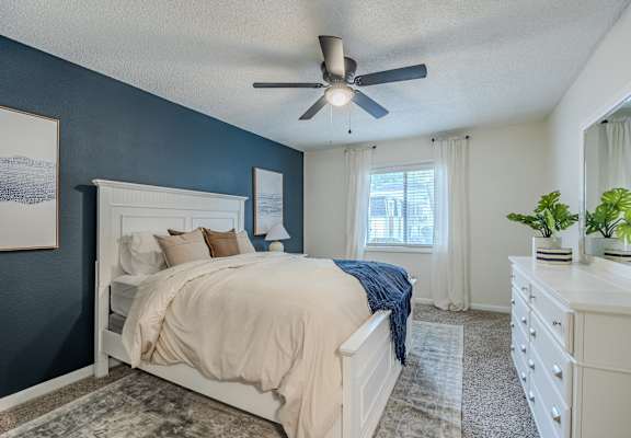 the master bedroom has a large bed and a ceiling fan