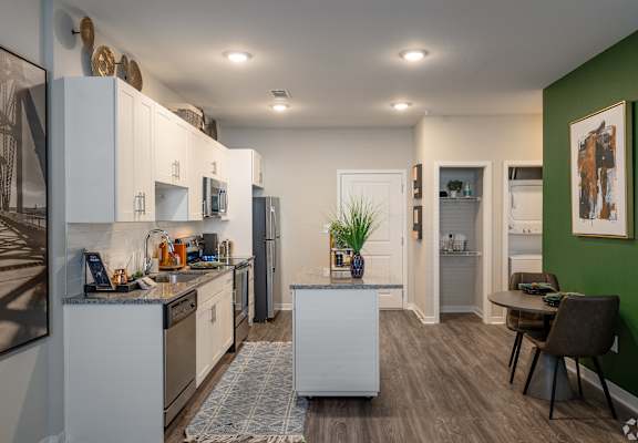 a kitchen and dining room with white cabinets and a green wall