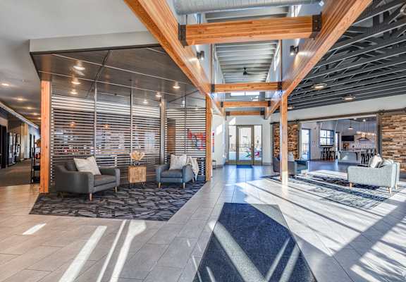 A modern living room with a wooden ceiling and a stone wall.
