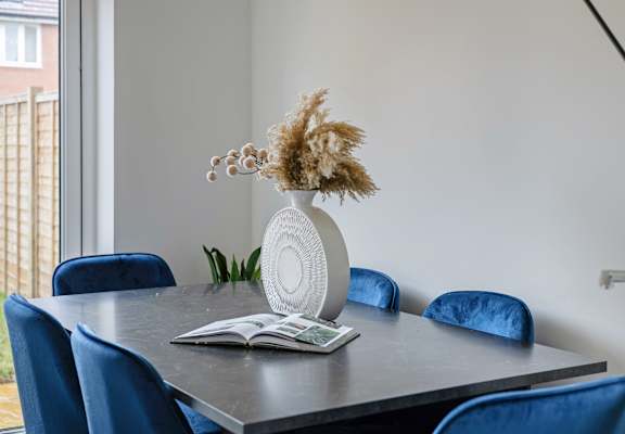 A dining table with a vase and a book on it.