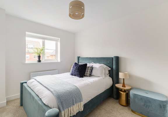 A bedroom with a bed, a lamp, and a window.