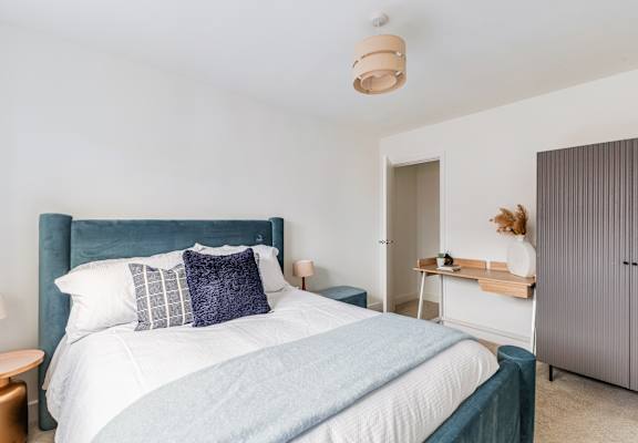 A bedroom with a large bed and a wooden nightstand.