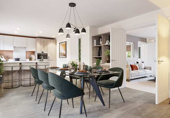 a living area with a dining table and chairs and a kitchen in the background