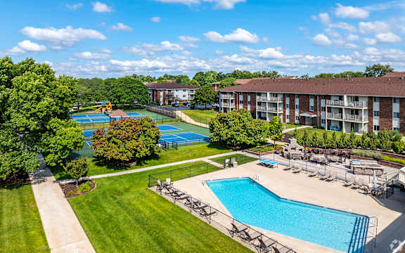 A large swimming pool surrounded by trees and a building in the background.