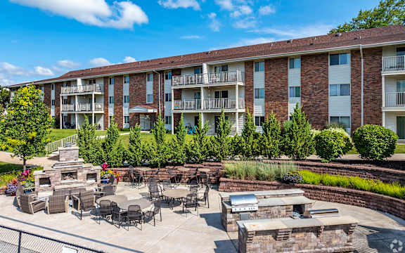 A sunny day at a brick apartment complex with a patio and fire pit.