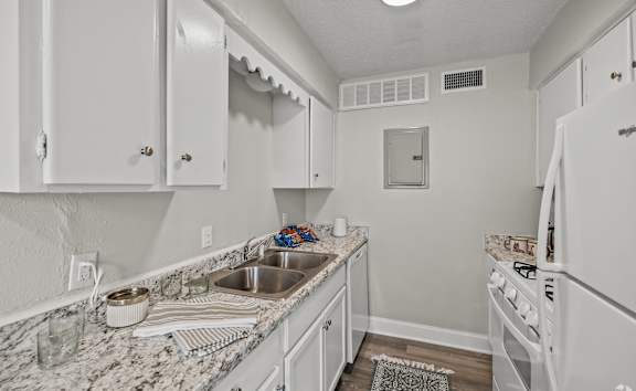 A kitchen with white cabinets and appliances. at La Bella Apartments, Fort Worth, Texas
