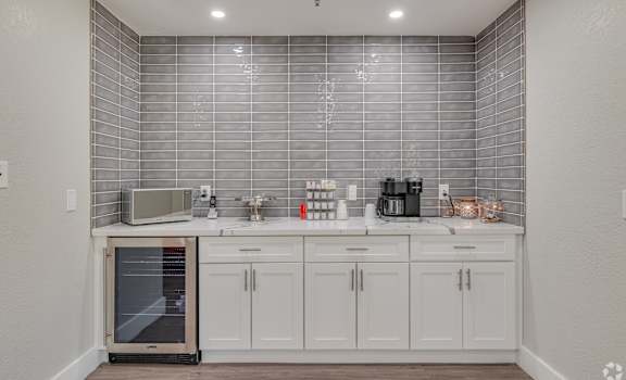 a kitchen with white cabinets and stainless steel appliances and a tiled wall