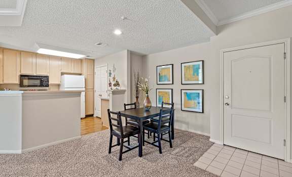 a dining area with a table and chairs and a kitchen in the background