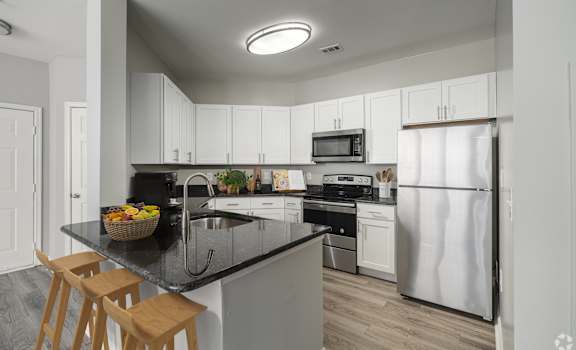 A kitchen with white cabinets and a black countertop.
