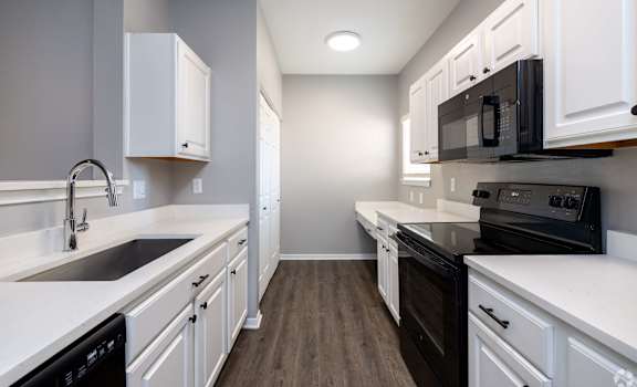 A kitchen with white cabinets and black appliances.
