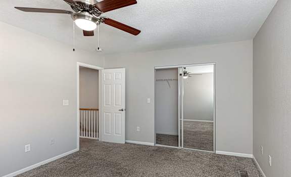 A room with a ceiling fan and two doors, one of which is open.