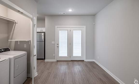 a laundry room with a washer and dryer and a door to a kitchen