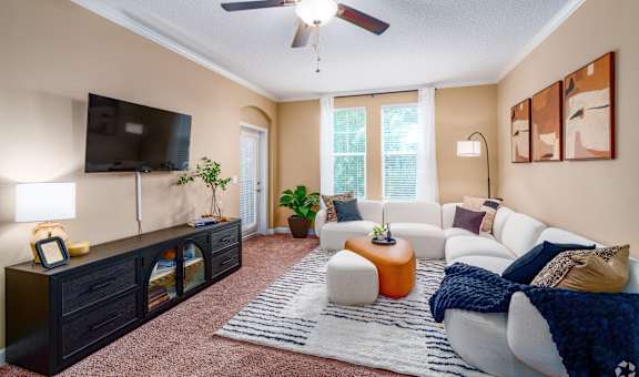 A living room with a white couch, a television, and a rug.