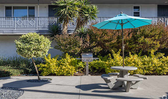 A blue umbrella is on a table in the middle of a courtyard.