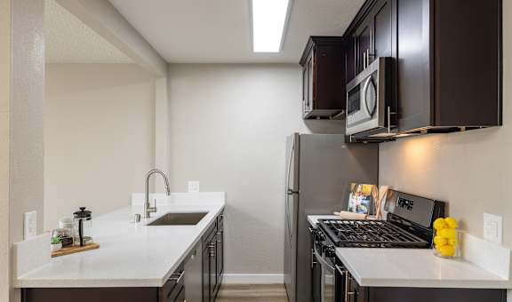 A kitchen with a white counter top and black appliances.