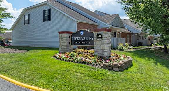 A sign for River Valley Apartments is in front of a building.
