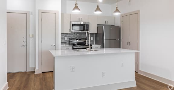 A kitchen with white cabinets and a white island with a microwave and oven built into it.