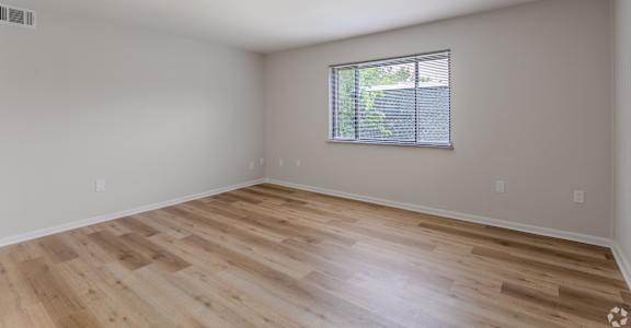 Empty room with wooden flooring and a window.