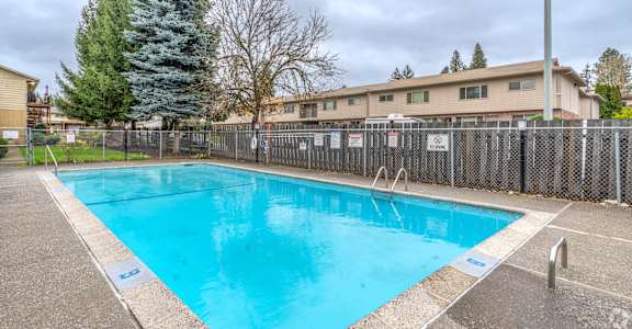 A large outdoor swimming pool surrounded by a fence.