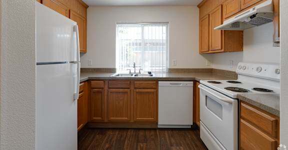 A kitchen with white appliances and wooden cabinets.