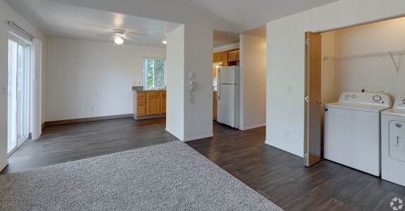 A spacious living room with a grey rug in the center.
