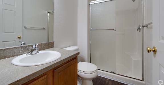 A white bathroom with a toilet, sink, and shower.