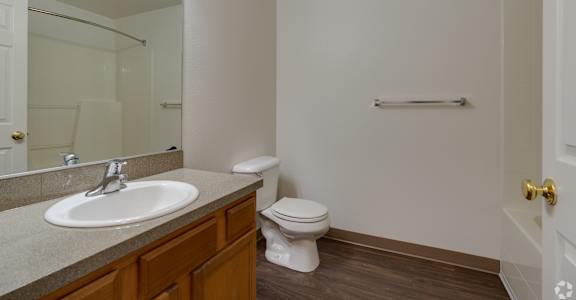 A bathroom with a toilet, sink, mirror, and towel bar.