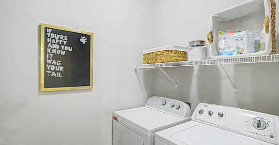 A laundry room with a washer and dryer and a sign on the wall.