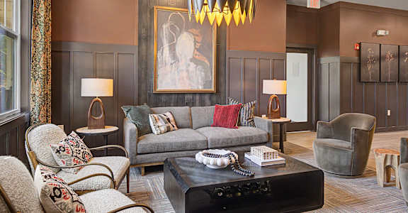 A living room with a grey couch, a coffee table, and a large painting on the wall.