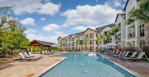 A large swimming pool surrounded by lounge chairs and palm trees.