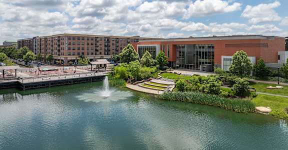 A fountain in the middle of a lake in front of a building.